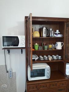 a microwave on a shelf next to a kitchen at Doroteafarm, dove saltiamo sull'amore e i sogni in Scalea