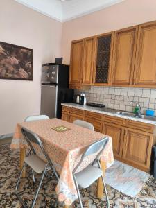 a kitchen with a table with chairs and a refrigerator at la casa del viaggiatore in Bronte