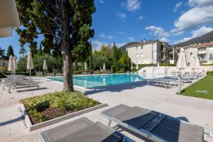 a swimming pool with chairs and umbrellas at Corte Fasanella 33 in Toscolano Maderno