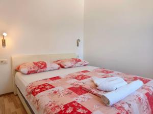 a bed with two pillows and a quilt on it at Apartments Pine in Primošten