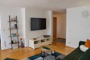 a living room with a couch and a tv on a wall at Ferienwohnung NORA - direkt am Bodensee in Friedrichshafen