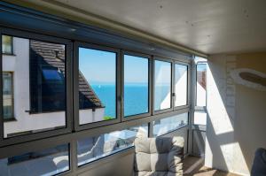 a room with windows and a chair and the ocean at Ferienwohnung NORA - direkt am Bodensee in Friedrichshafen