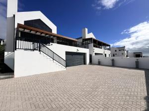 a white building with a garage and a sky at Swordfish Retreat in St. Helena Bay