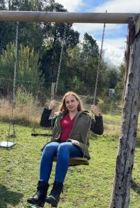 a woman sitting on a swing in a field at Cabañas Troncos de Relin in Panguipulli