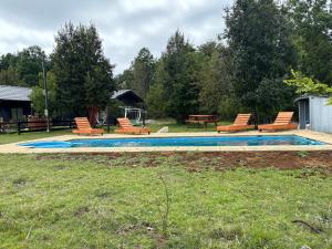 a swimming pool with chairs and a picnic table at Cabañas Troncos de Relin in Panguipulli