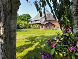 a large house with a yard with purple flowers at Ferienwohnung Hoffarth 1 in Gelting