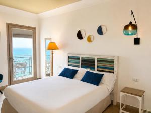 a bedroom with a large white bed with blue pillows at Domus Maris Relais Boutique Hotel in Sciacca