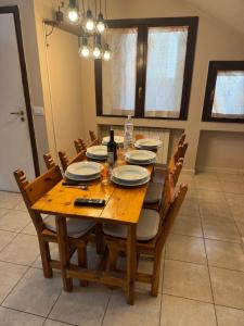a wooden table with chairs and plates and bottles of wine at La Casa di Maya a due passi da Sestriere in Grange Sises