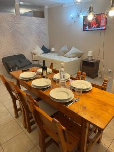 a wooden table with chairs and plates and a couch at La Casa di Maya a due passi da Sestriere in Grange Sises