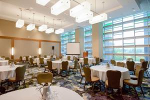 a conference room with tables and chairs and a screen at Coast Coal Harbour Vancouver Hotel by APA in Vancouver