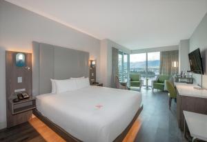 a hotel room with a white bed and a desk at Coast Coal Harbour Vancouver Hotel by APA in Vancouver +47 photos