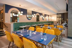a restaurant with blue tables and yellow chairs at Coast Coal Harbour Vancouver Hotel by APA in Vancouver