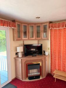 a living room with a flat screen tv and a entertainment center at Swans Rest - Lakeside Caravan Park in Denver