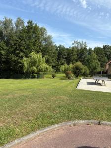 a park with a picnic table in the grass at Appartement avec piscine chauffée et Tennis proche Deauville in Touques