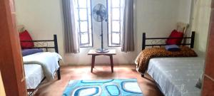 a bedroom with two beds and a table with a fan at Apartment-double storey-2 bedrooms-own bathroom, kitchen, dining room, entrance, lounge, patio in Pinetown