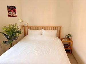 a bedroom with a bed with white sheets and a plant at Stay Joy in Suwon