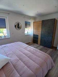 a bedroom with a large bed and two windows at Ferienwohnung Sägmühlweiher in Ludwigswinkel