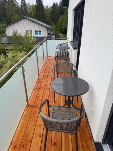 a table and two chairs on a balcony with a table at Ferienwohnung Sägmühlweiher in Ludwigswinkel +3 photos