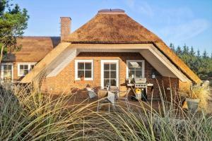 a small brick house with a thatched roof at 1126-Ringkobing-Frans-Julius-Vej-44 in Klegod