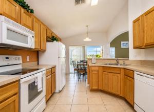 a kitchen with wooden cabinets and white appliances at 5BR Florida villa with private pool in Davenport