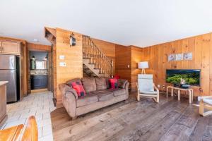 a living room with a couch and a staircase at Spa Pool table Mountain - Chalet Avalanche in Saint-Philémon