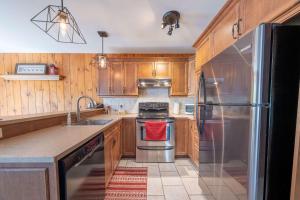 a kitchen with wooden cabinets and a stainless steel refrigerator at Spa Pool table Mountain - Chalet Avalanche in Saint-Philémon +36 photos