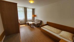 a bedroom with a bed and a chair and a window at Apartmenthaus Salzburger Hof in Bad Reichenhall