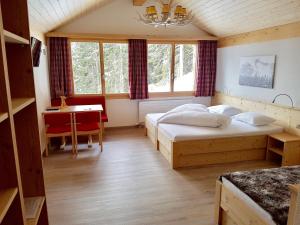1 dormitorio con 2 camas, mesa y escritorio en Bischofalp, en Elm