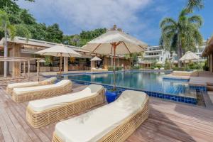 a swimming pool with lounge chairs and umbrellas at NEW Serenity Tropical 2 Bed Condo On Beachfront in Ban Saiyuan (1)