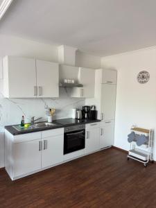 a kitchen with white cabinets and a stove top oven at Hotel MeerLand Pellworm in Pellworm