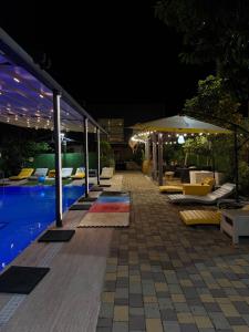 a pool with lounge chairs and umbrellas at night at Hotel Smile in Kobuleti