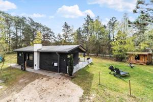 a small black cabin with a porch in a yard at 84100-Ebeltoft-Magevej-4 in Ebeltoft