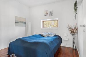 a bedroom with a bed with blue sheets and a window at 8250-Ega-Strandvangsvej-52 in Egå