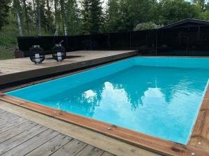 a swimming pool with a wooden deck and blue water at Villa Ensola with pool in Savonlinna