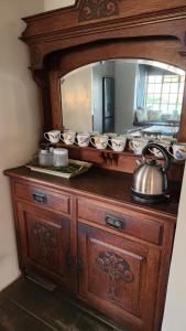 a wooden dresser with a mirror and a tea kettle on it at FinchDen House in Bulawayo +5 photos