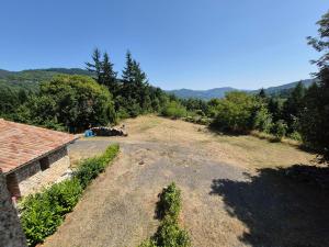 an empty field next to a house with trees at Tranquillité in Le Cheylard