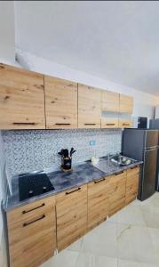 a kitchen with wooden cabinets and a sink and a stove at Mimoza Appartament in Golem