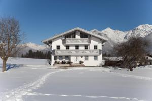 a white house in the snow with mountains at Gästehaus Weber in Oberperfuss