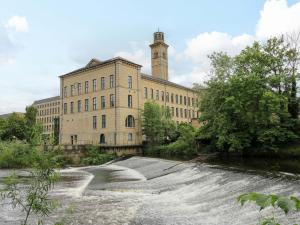 a building with a clock tower on top of a river at Saltaire House in Saltaire