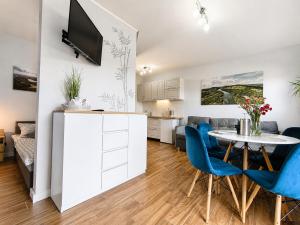a kitchen and living room with a table and blue chairs at Willa Panorama 881-751-206 in Polańczyk