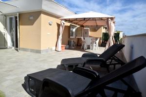 a group of chairs and an umbrella on a patio at CasaKami Sky Terrace in Nettuno