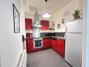 a kitchen with red cabinets and a white refrigerator at Cosy Magnolia Quartz - T3 - Hyper centre avec Parking in Pau +19 photos