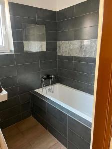 a bathroom with a bath tub with black tiles at Hospodářství u kapličky in Kladeruby nad Oslavou