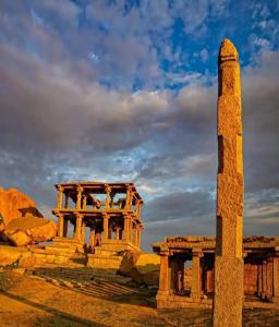 a pillar and a building in the desert at Budha Home Stay in Hampi