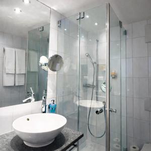 a bathroom with a glass shower and a sink at Hotel Alpina Parpan in Parpan +51 photos