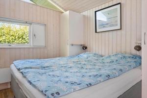 a bedroom with a bed with a blue comforter and a window at 1627-Dronningmolle-Svalevej-3 in Dronningmølle
