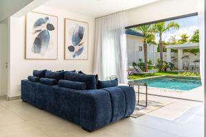 a living room with a blue couch and a pool at Villa Solis - Elegant & Modern Private Pool Escape in Cap Malheureux