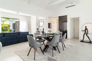 a living room with a dining table and a blue couch at Villa Solis - Elegant & Modern Private Pool Escape in Cap Malheureux