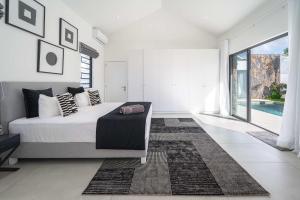 a white bedroom with a bed and a large window at Villa Solis - Elegant & Modern Private Pool Escape in Cap Malheureux