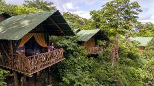 een vrouw op het balkon van een boomhut bij La Tigra Rainforest Lodge in Fortuna